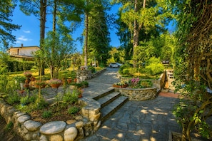 A stone pathway leading to a house surrounded by lush greenery and potted plants. - Villa I Tre Archi for 6 With Private Garden (Pisano)
