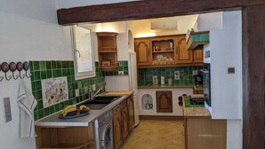 Une cuisine de taille réduite équipée d’un lave-linge, d’un évier et d’une cuisinière.
