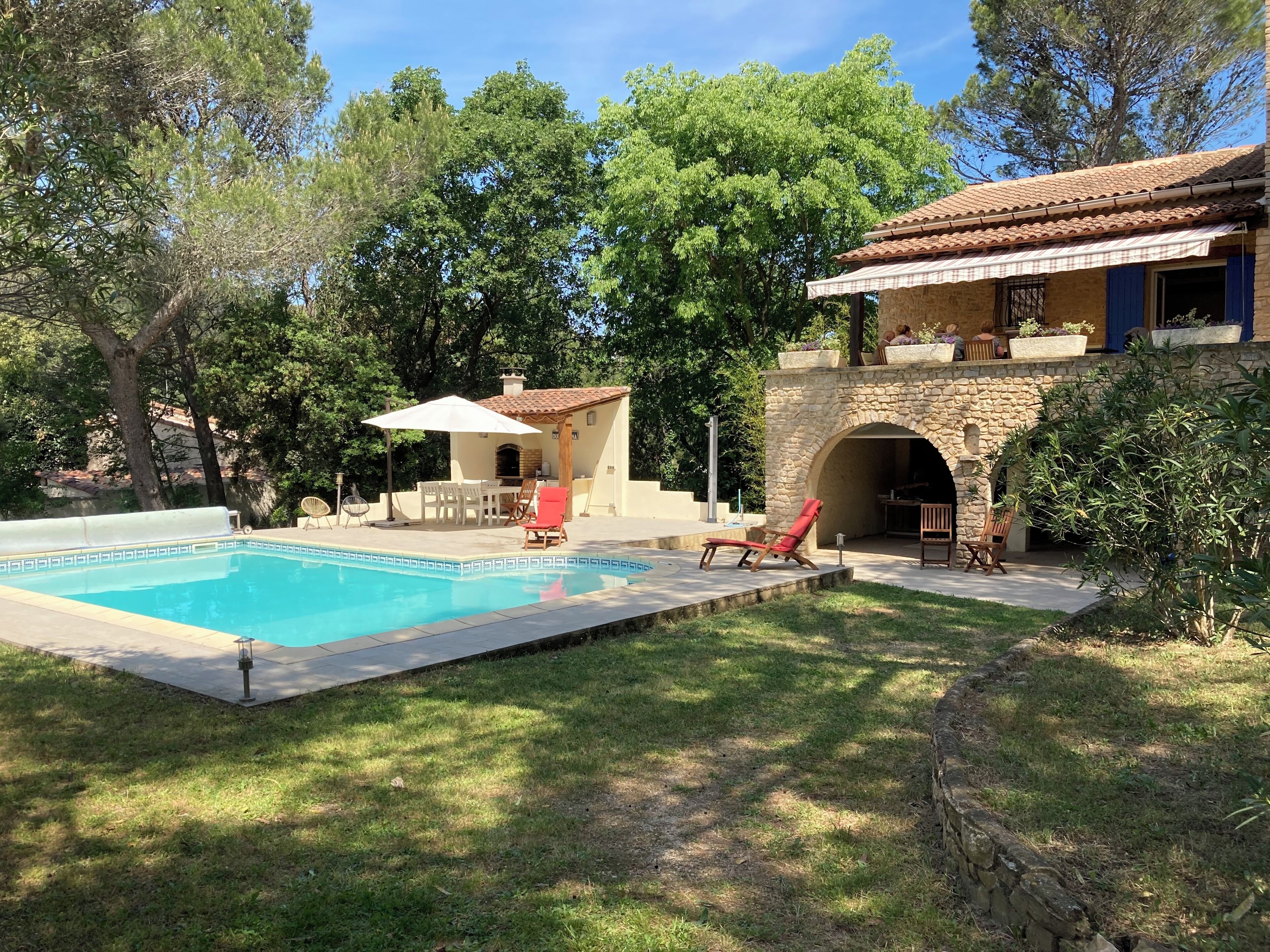 Un espace piscine agrémenté d’un mur en pierre, d’un coin salon abrité et d’une arche en pierre.