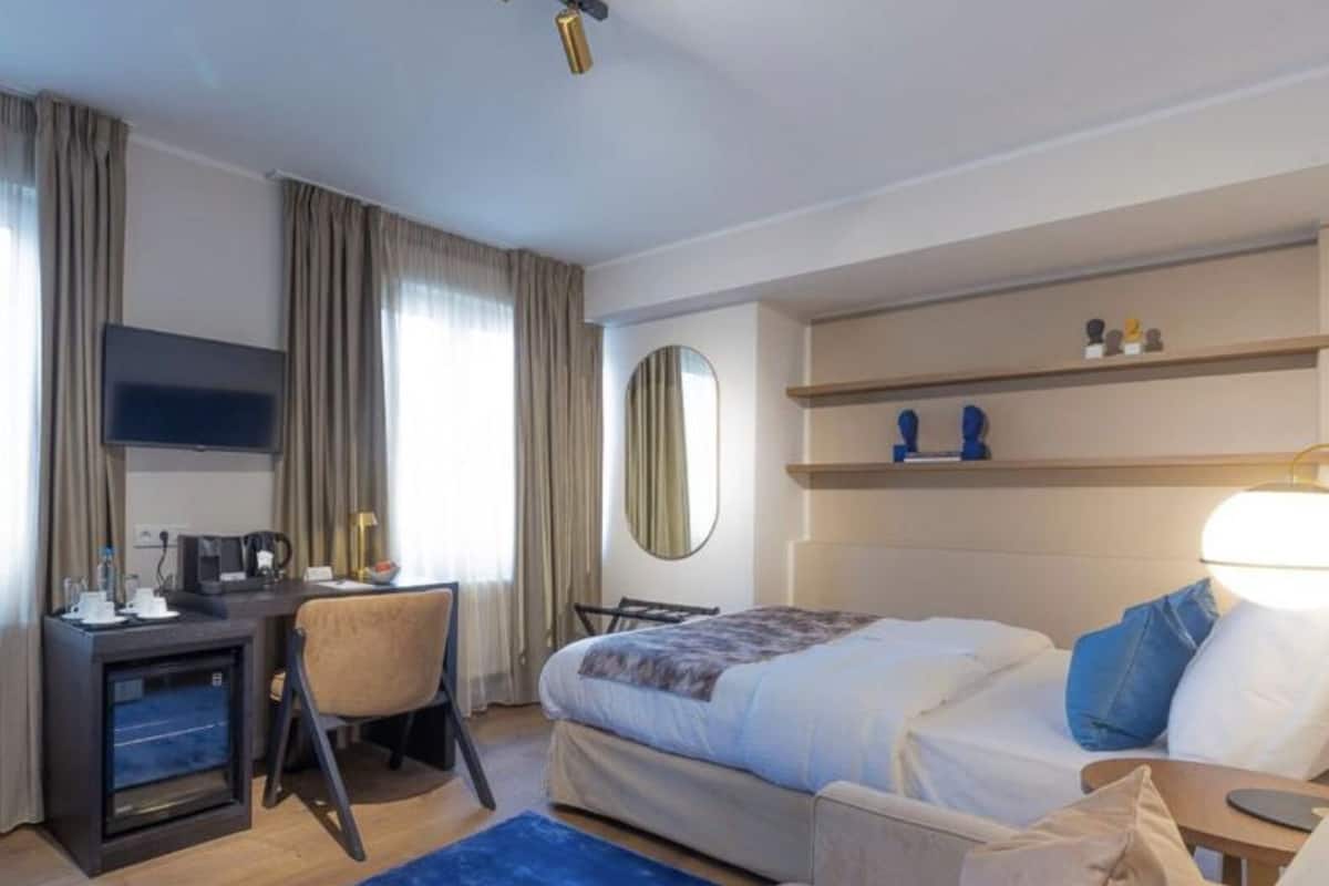 A hotel room with a bed, desk, chair, and a TV.