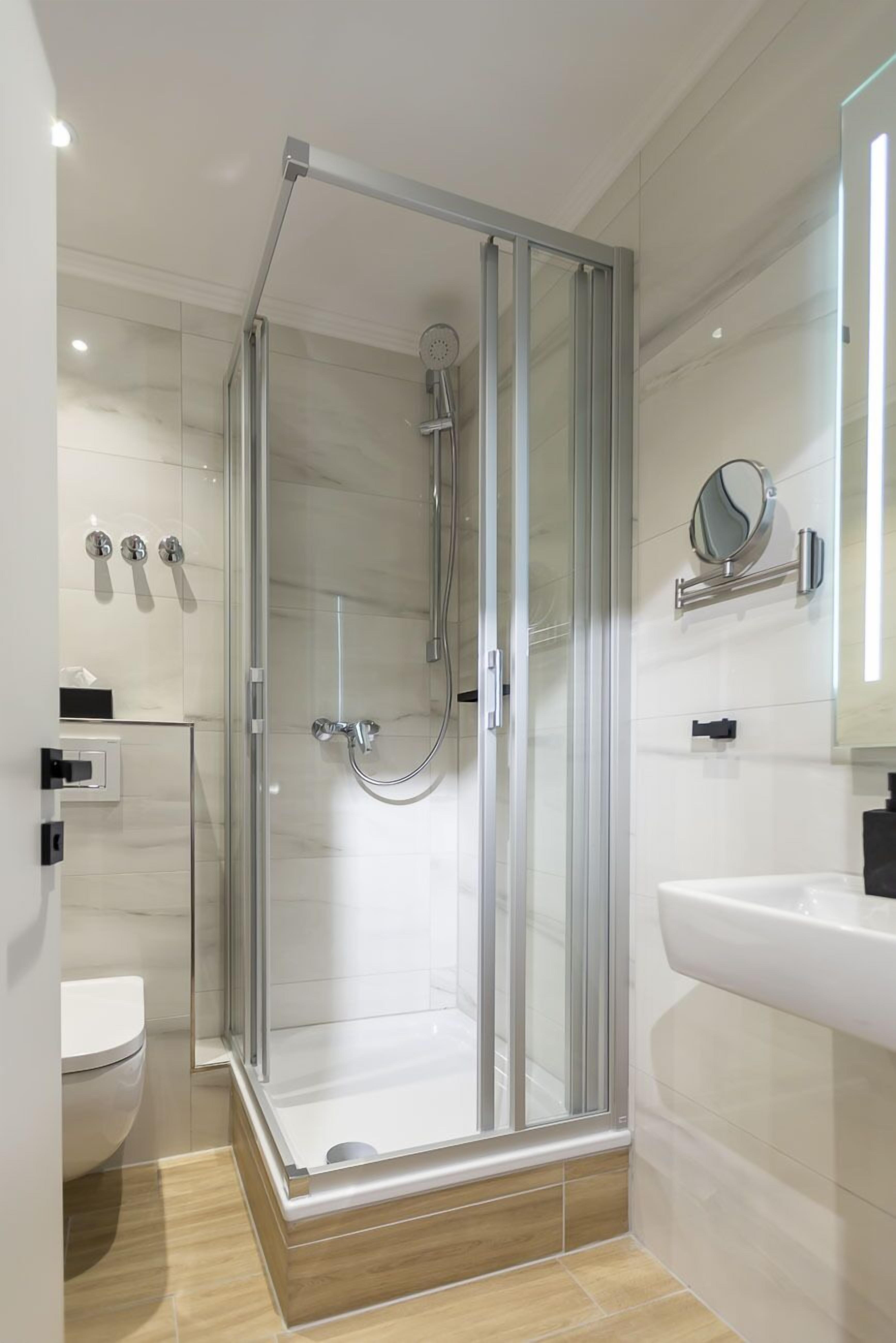 Une salle de bain moderne avec une douche à parois de verre, un lavabo blanc et un miroir au mur.
