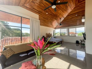 Un salon moderne avec un plafond en bois, de grandes fenêtres, un canapé et une plante décorative.