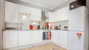 A modern kitchen with white cabinets, a built-in oven, and a refrigerator. - Watford WD18 - Homely 2Bedroom/1Bathroom Flat w/ FREE WIFI & FREE PARKING (Watford)
