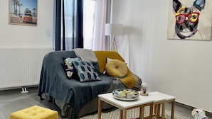 Un salón moderno con un sofá, dos otomanos amarillos, una mesa de centro y un cuadro de un gato en la pared.