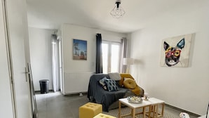 Una sala moderna con un sofá, dos otomanos amarillos, una mesa de centro y una pequeña mesa blanca con adornos.