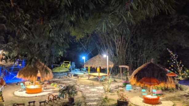 An outdoor area with thatched-roof structures, seating arrangements, and a small pool. - Camping Ground Taman Nggirli (Srimulyo)