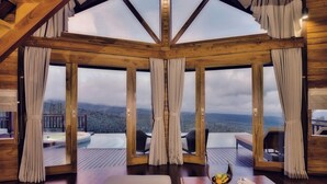 Un interior de fusta amb grans finestres que donen vista a un paisatge boscós.