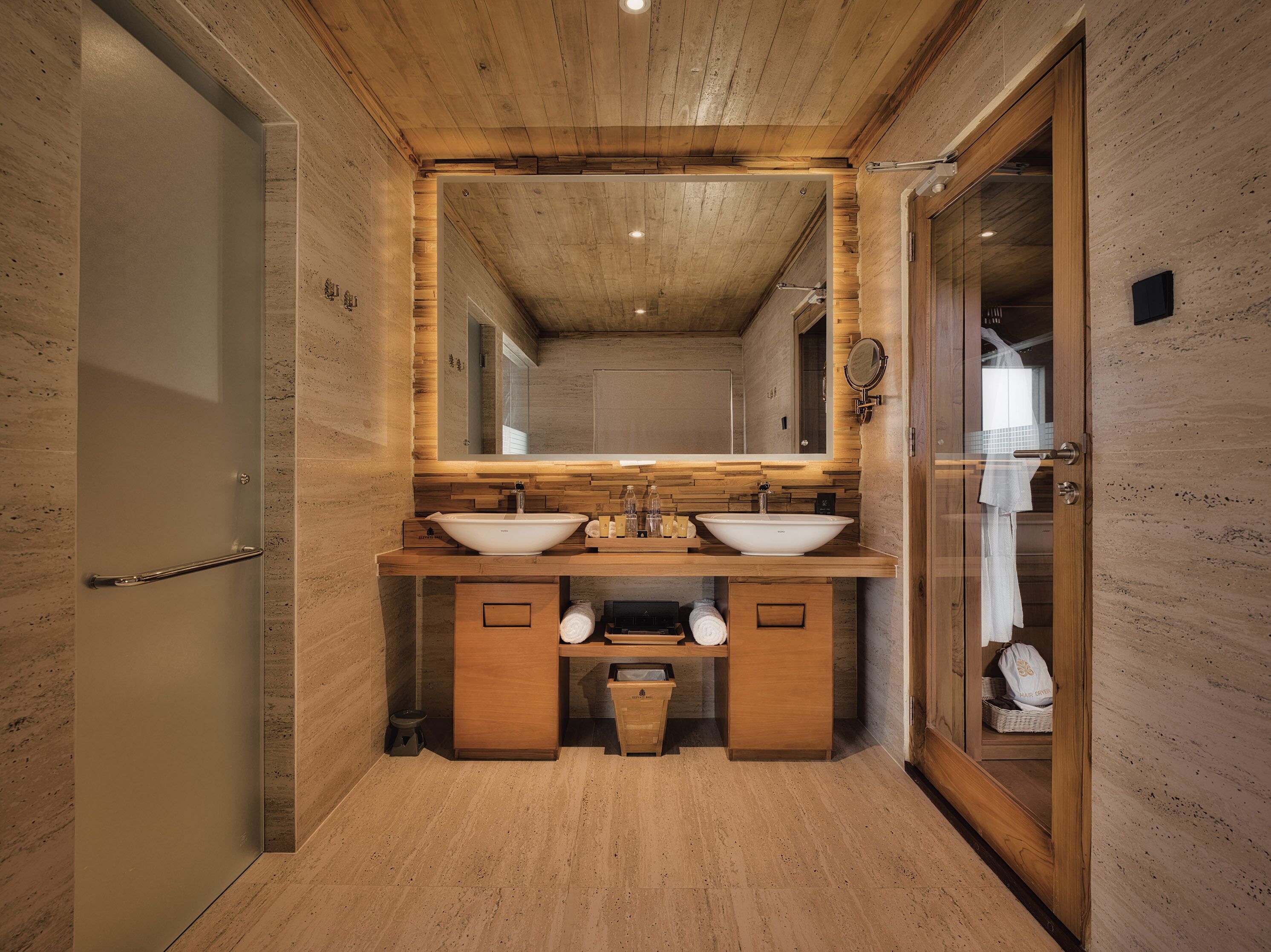 A modern bathroom with wooden accents, a large mirror, and two sinks.