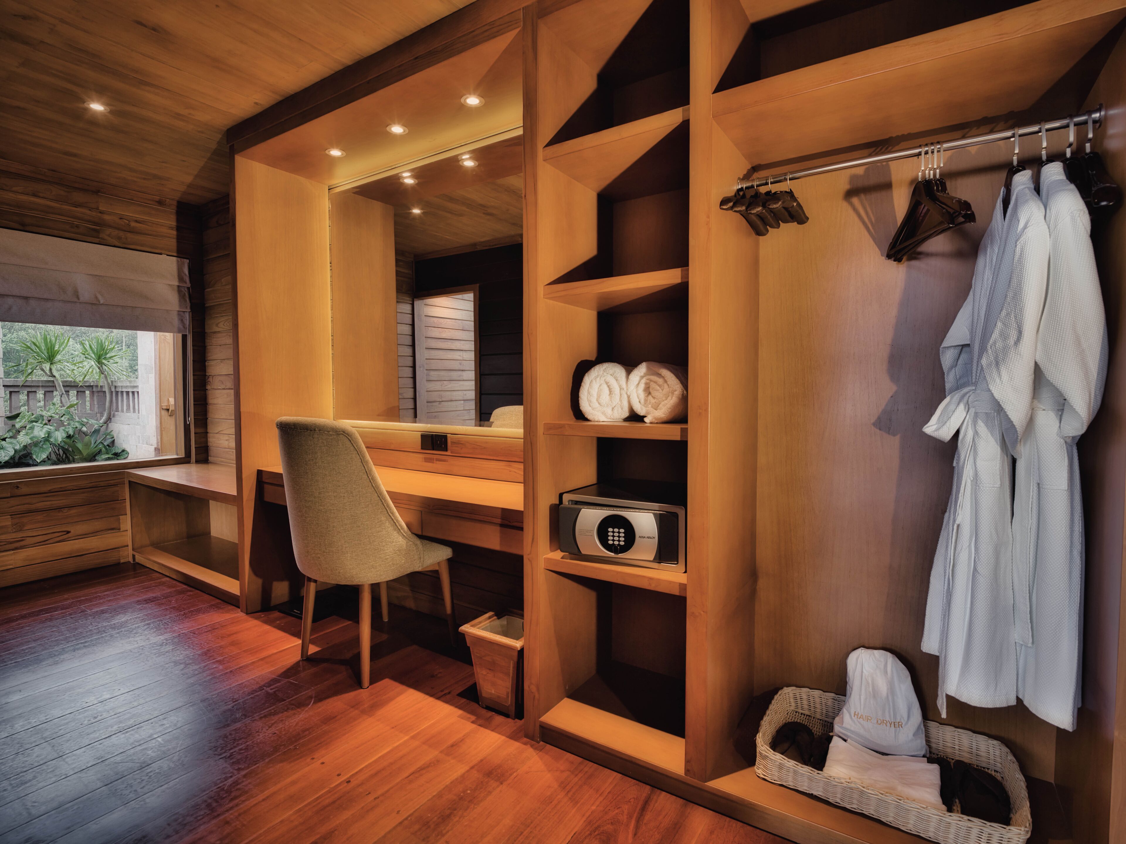 A modern bathroom with wooden cabinetry, a built-in shower, a hair dryer, and a towel rack.
