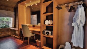 A modern bathroom with wooden cabinetry, a built-in shower, a hair dryer, and a towel rack.