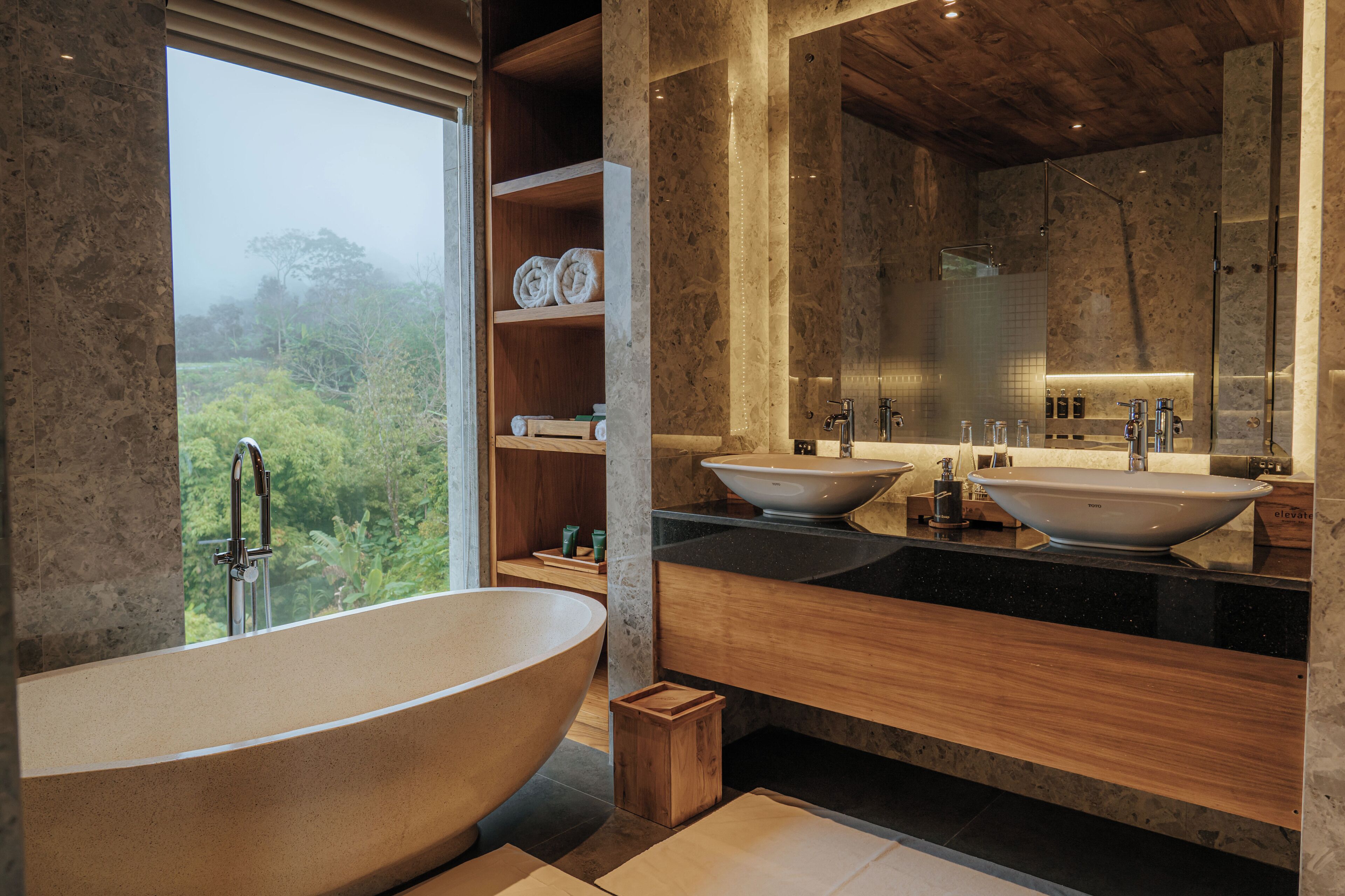 A modern bathroom with a freestanding bathtub, two sinks, and a large mirror.