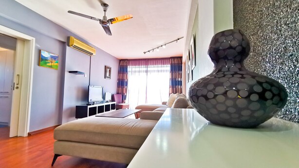 Uma sala de estar moderna com um sofá, uma televisão, um ventilador de teto e um vaso decorativo.