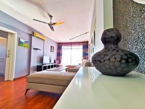 Una sala de estar moderna con un sofá, televisor, ventilador de techo y un jarrón decorativo.