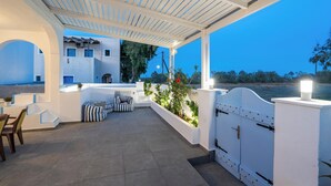 A covered outdoor patio with seating, a view of the landscape, and a building in the background. - Villa Kocis with Private Pool (Santorini)