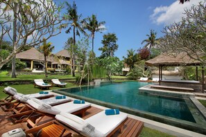A pool area with lounge chairs and a thatched-roof structure. - Istana Semer (Kerobokan)