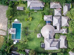 An aerial view of a resort with a swimming pool, thatched-roof structures, and lush greenery. - Istana Semer (Kerobokan)