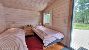 Cozy cabin with two single beds, a dresser, and a nightstand, offering a warm and inviting atmosphere.