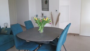 A dining area with a round table, blue upholstered chairs, and a vase with yellow and pink tulips.