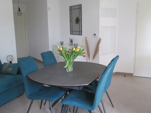 A dining area with a round table, blue upholstered chairs, and a vase with yellow and pink tulips.