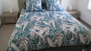 A bed with a patterned bedspread, two pillows, and two bedside tables with lamps.