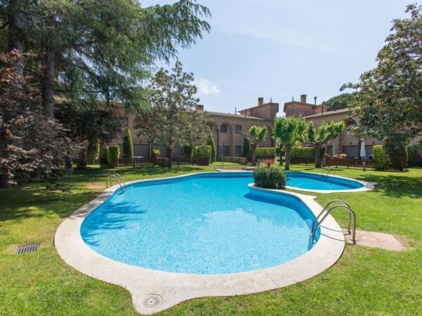 A swimming pool with a surrounding grassy area and trees. - Cabanyes Club by Interhome (Calonge)