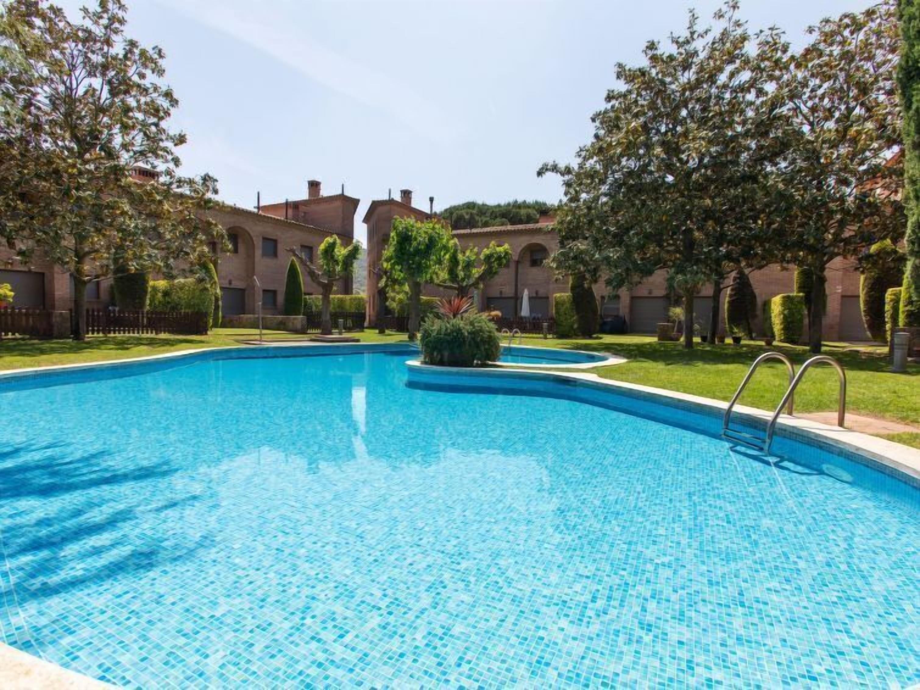 A swimming pool with a clear blue water surface, surrounded by well-maintained grass and trees.