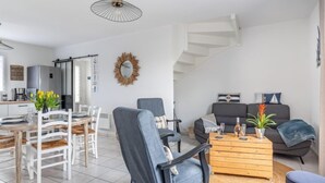A modern living space with a dining area, a sofa set, and a staircase leading to another level. - La Perle de Damgan by Interhome (Damgan)