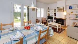 Un comedor con una mesa dispuesta para cuatro personas, una chimenea y una estantería.