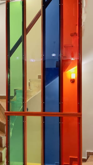 Staircase leads to an upper floor, surrounded by vibrant color panels and clean lines.