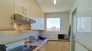 Cocina compacta con estufa, microondas y ventana con vistas a la ciudad.
