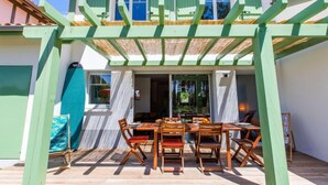 A two-story house with a covered patio area featuring a dining table and chairs. - Les Fougères by Interhome (Moliets)