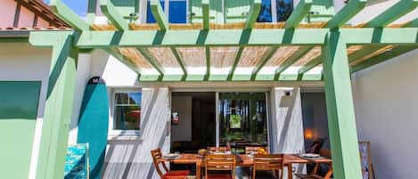 A two-story house with a covered patio area featuring a dining table and chairs.