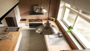 Et moderne køkken med en murstensbagevæg, rustfrie stålapparater og en hængende lampe.