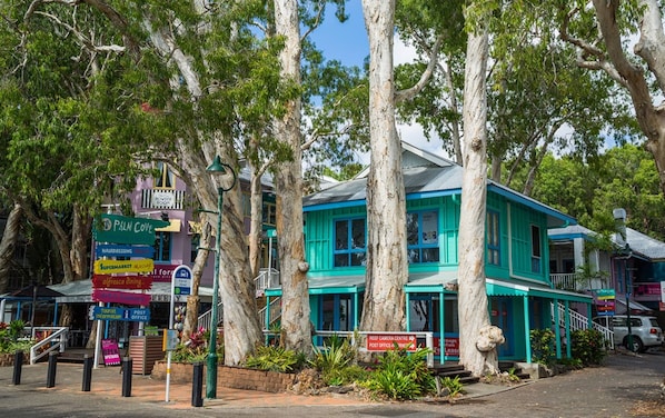 A two-story building with a turquoise facade, surrounded by trees.