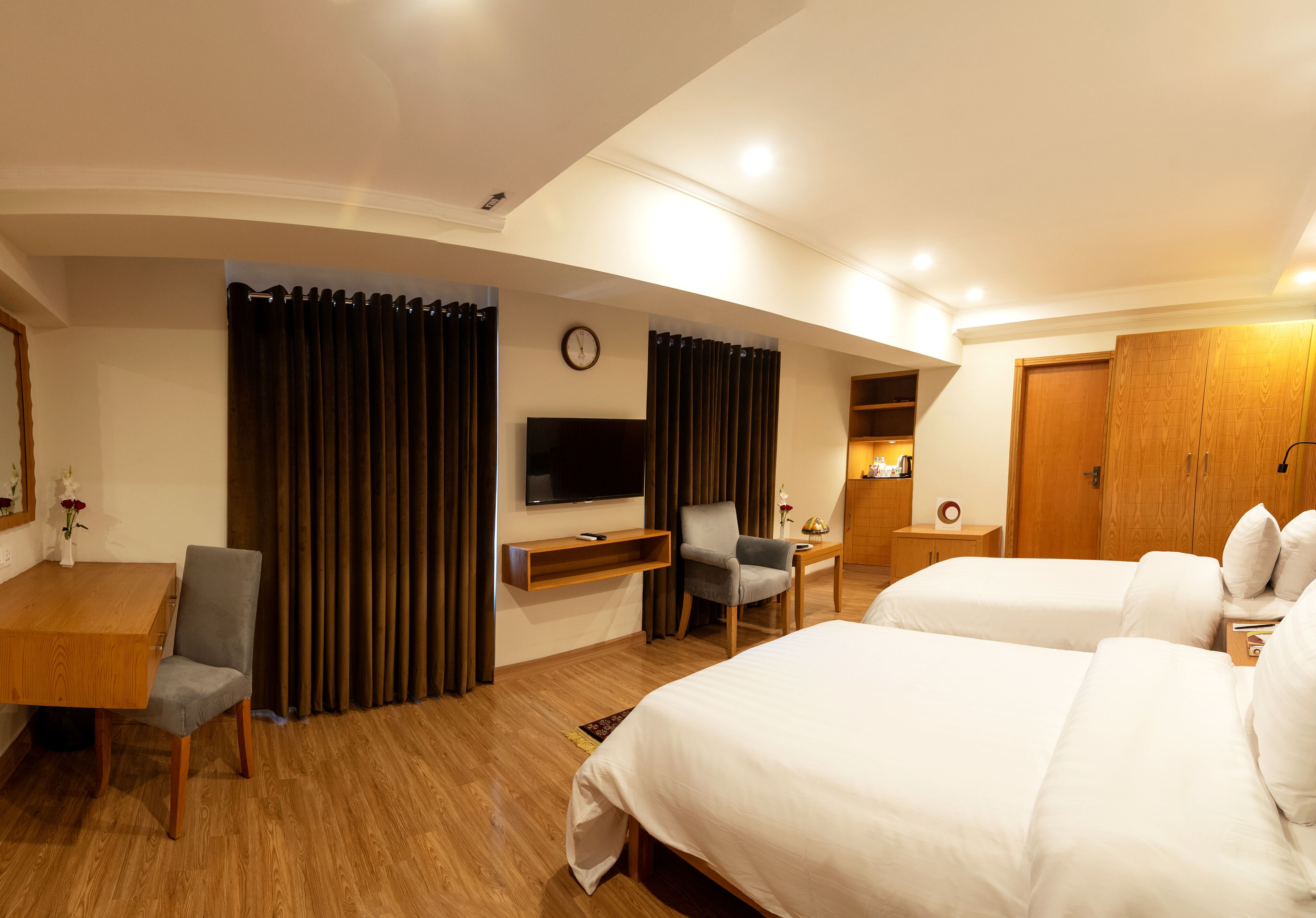 Ein Hotelzimmer mit einem Holztisch, einem Fernseher, einem Bett und einem Sessel.