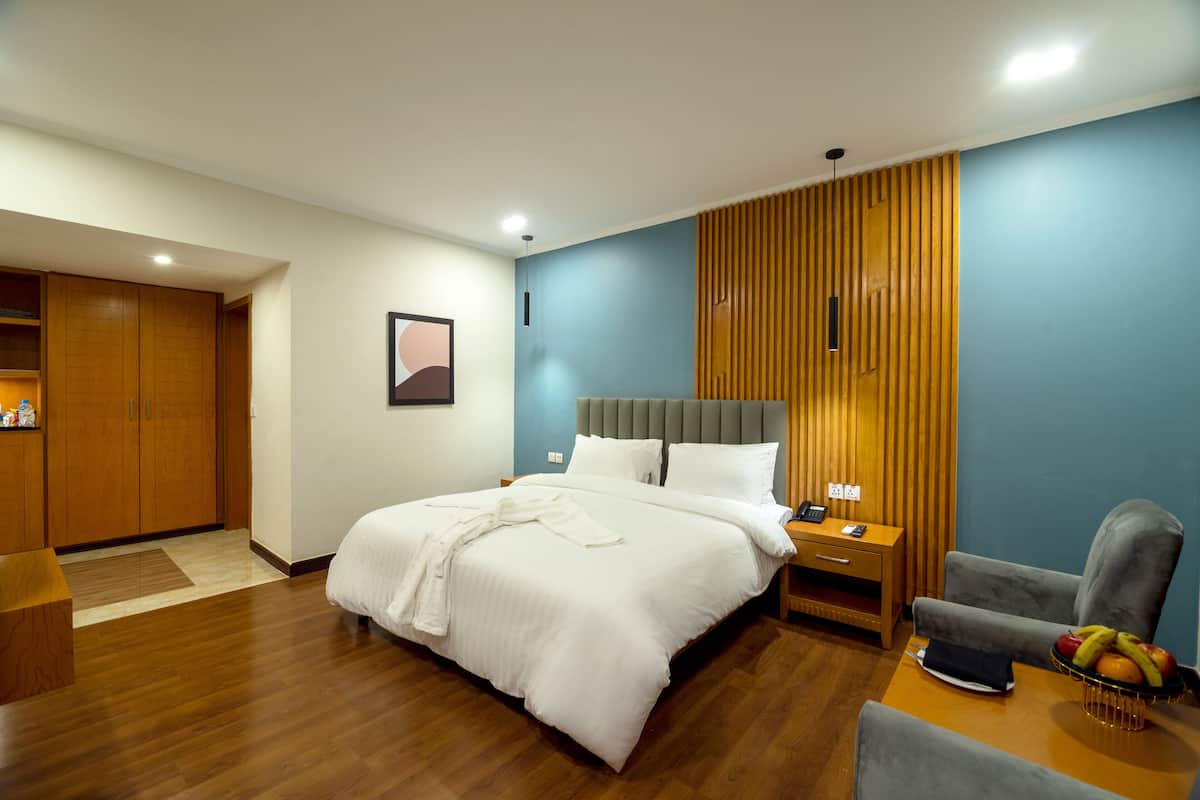 Una habitación de hotel con cama, mesita de noche, silla y un frutero.