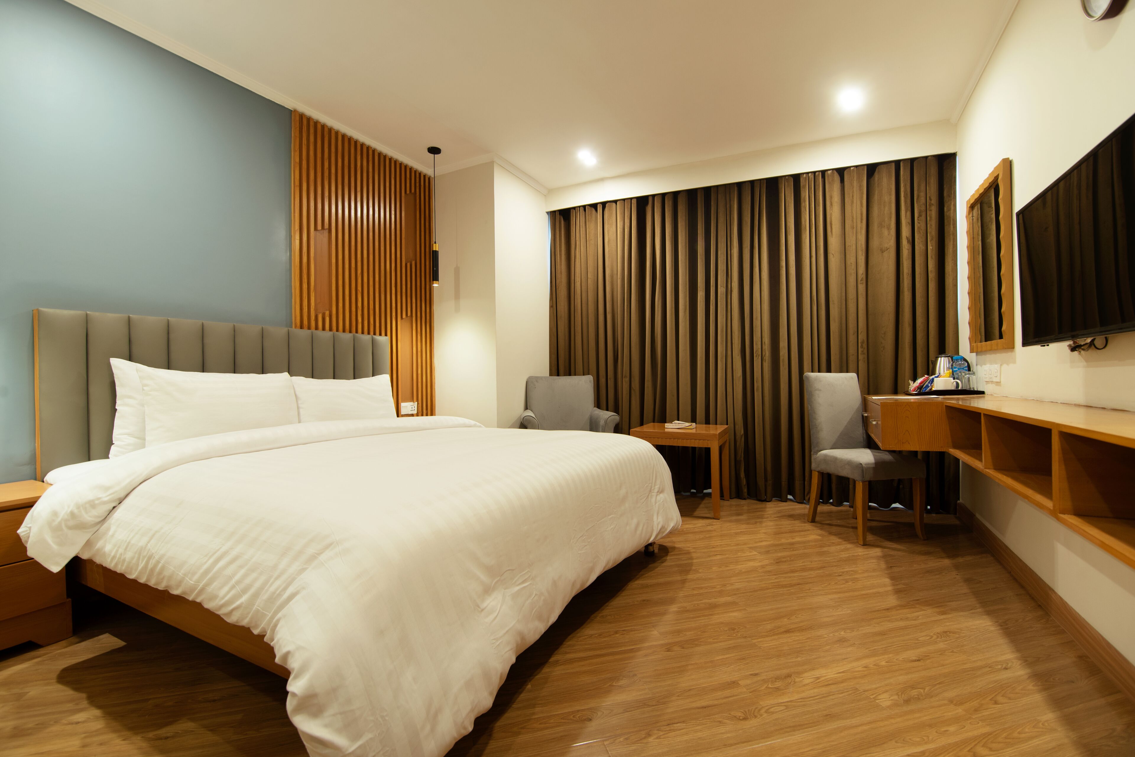 A hotel room with a large bed, two chairs, a desk, and a TV.