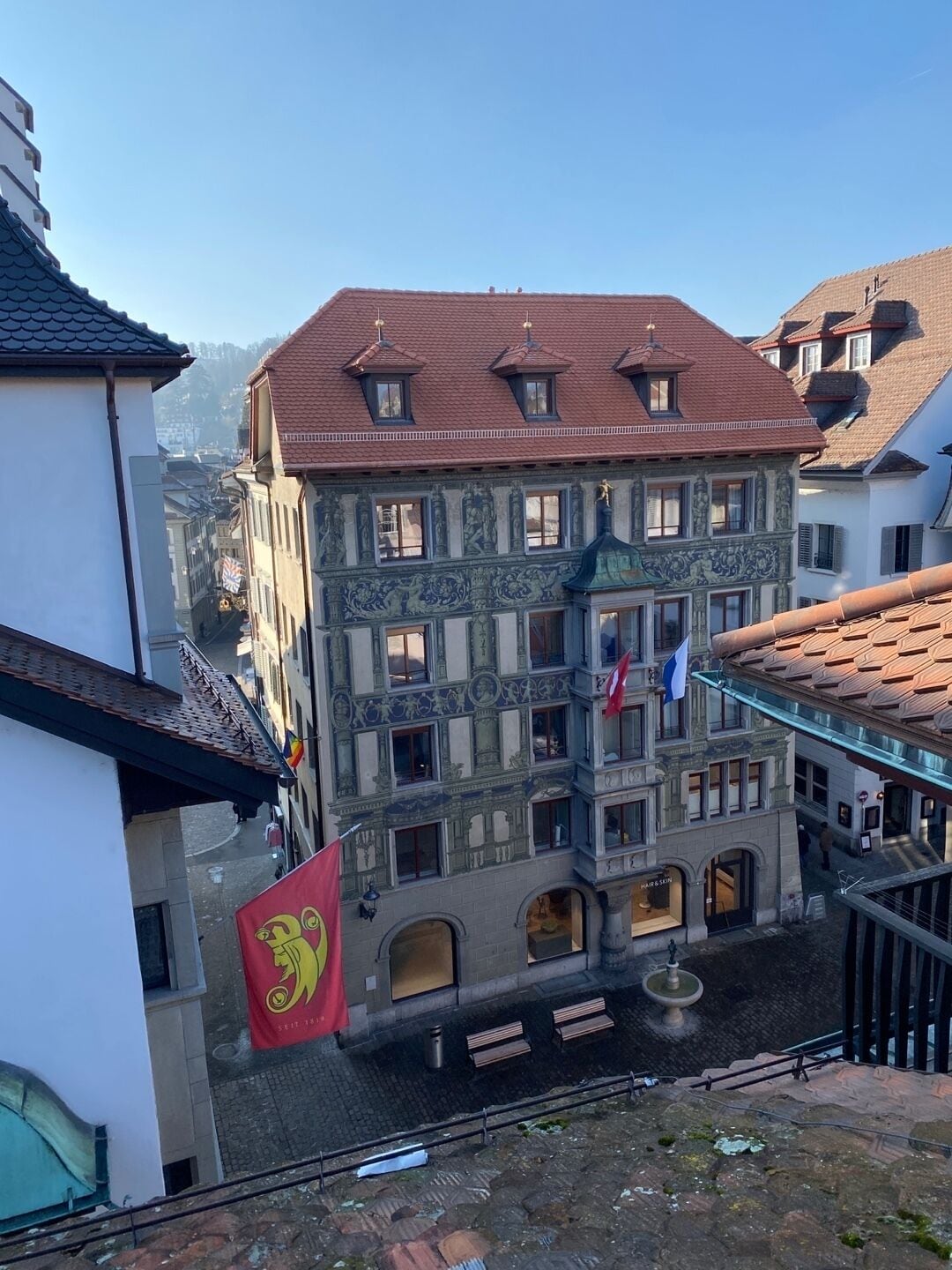 Un edificio histórico con fachadas ornamentadas y numerosas ventanas, situado en una zona urbana densamente construida.