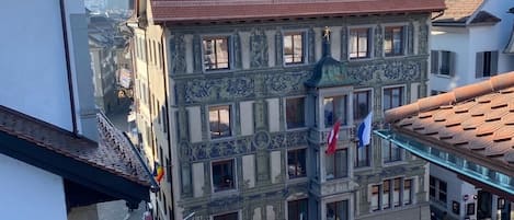 Un edificio histórico con fachadas ornamentadas y numerosas ventanas, situado en una zona urbana densamente construida.