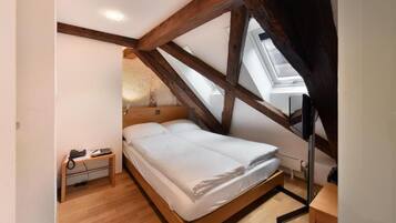 Un dormitorio con cama de madera, una mesita de noche con lámpara y un tragaluz.