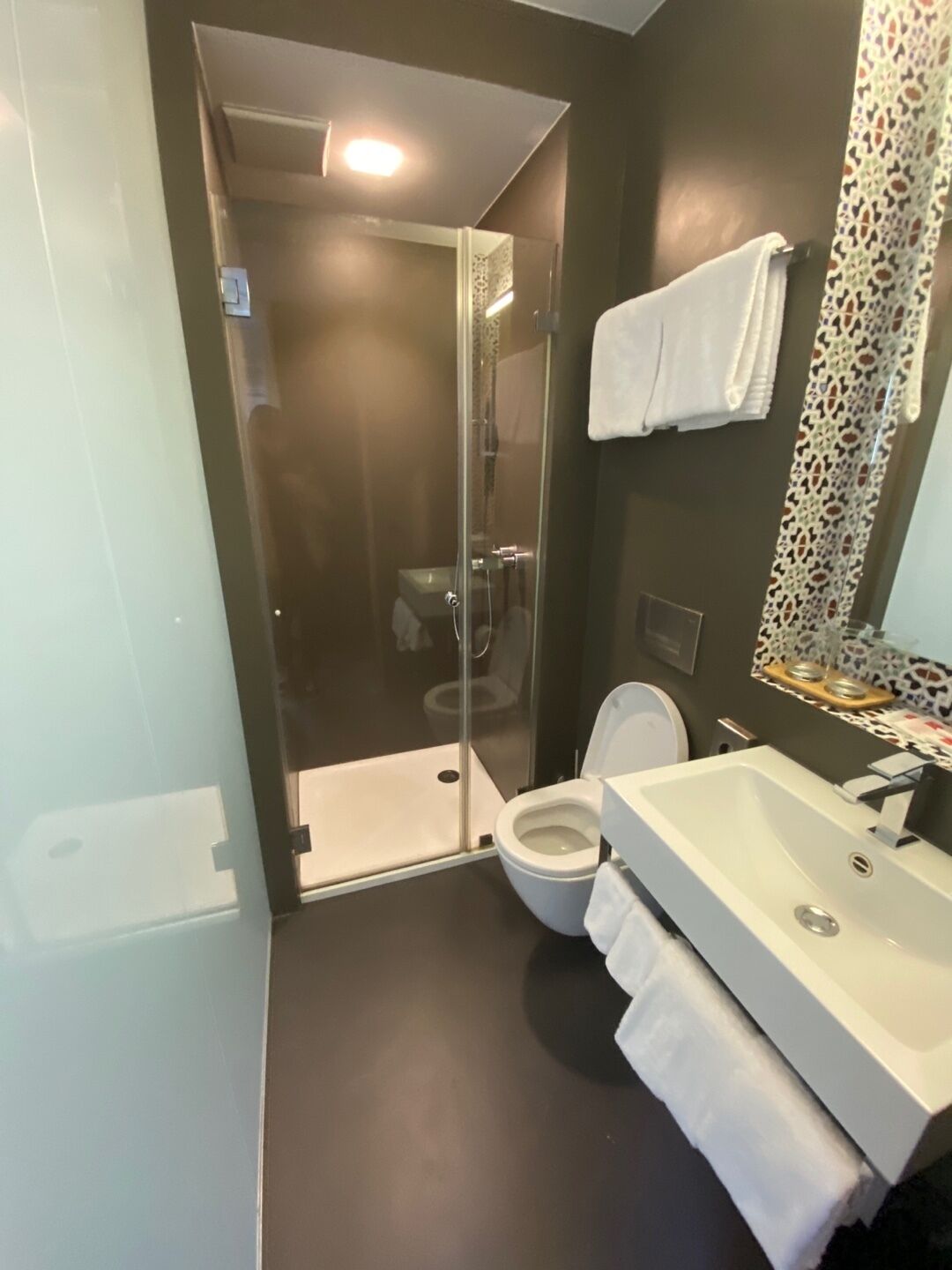 A modern bathroom with a glass-enclosed shower, a white toilet, and a vanity with a sink.