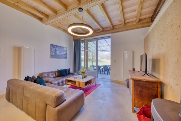 A modern living room with a leather sofa, wooden coffee table, and a TV on a wooden cabinet.