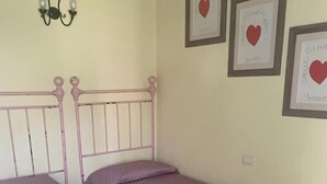 A bedroom with two single beds, a wall-mounted light fixture, and three framed pictures with hearts. - The villett 🏡 in the countryside a stone's throw from the sea (Pescia Romana)