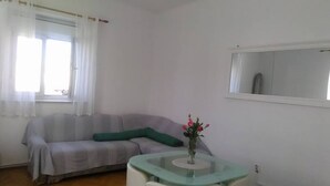 A living room with a sofa, a glass coffee table, and a vase with flowers. - Apartment Marjan (Posedarje)