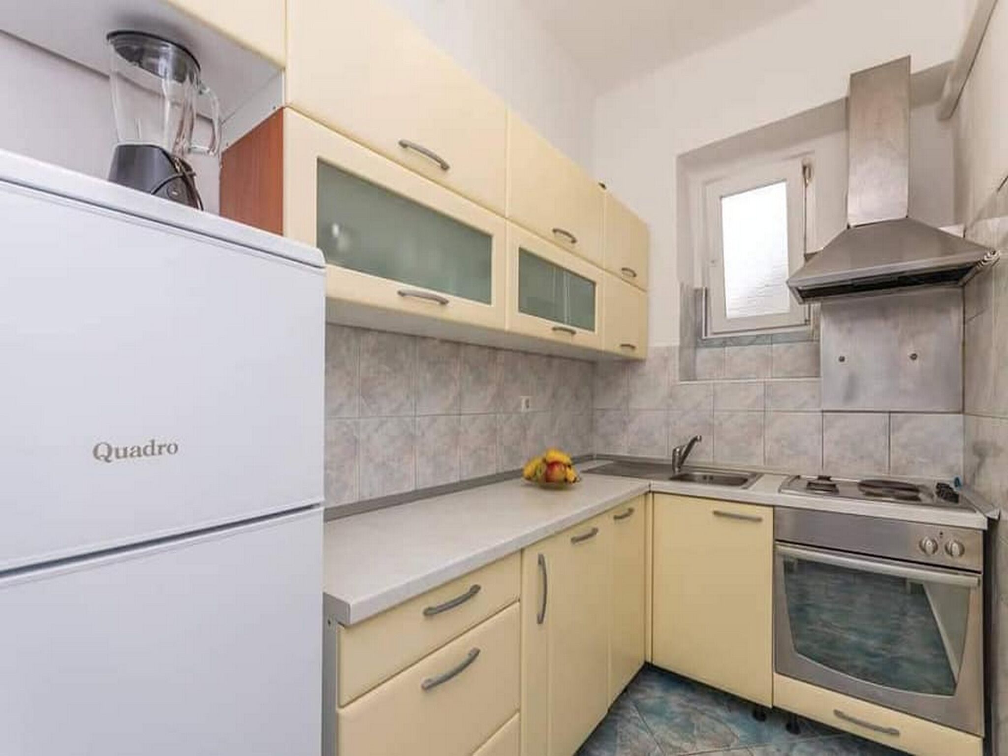 A compact kitchen with a refrigerator, a stove, and a window.