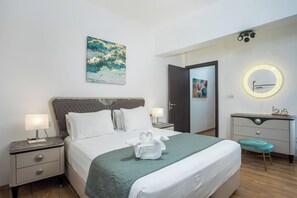 Une chambre d’hôtel bien rangée, avec un lit, des tables de chevet, un bureau et un miroir.