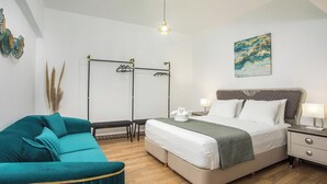Ein modernes Schlafzimmer mit einem Bett, einem Nachttisch und einem türkisfarbenen Sofa.
