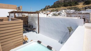 Eine Dachterrasse mit Whirlpool, Holzmöbeln und Blick auf eine historische Hügelburg.