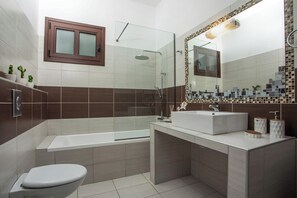Un baño moderno con ducha de vidrio, lavamanos blanco y retrete.
