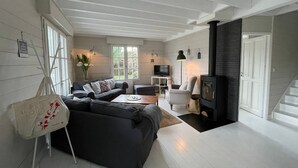 A modern living room with a black sofa, a coffee table, a TV, and a fireplace. - COSY house 600 m from the beach, ideal for families - (Agon-Coutainville)